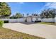 Well-maintained home exterior featuring a spacious driveway, white fence, and manicured landscaping at 5205 Saint Regis Pl, Belle Isle, FL 32812