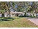 Charming single-story home with manicured lawn, brick driveway, mature trees, and white shutters at 5205 Saint Regis Pl, Belle Isle, FL 32812