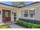 Elegant entryway featuring a wood door, sidelights, decorative wreath, and manicured boxwood hedges at 5205 Saint Regis Pl, Belle Isle, FL 32812