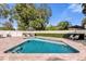 Inviting backyard pool with a stone surround, lounge seating, and a privacy fence with manicured hedges at 5205 Saint Regis Pl, Belle Isle, FL 32812