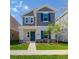 Charming two-story home with gray shingles, teal shutters, manicured lawn, and walkway at 6140 Shavasana Rd, Clermont, FL 34714