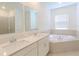 Bright bathroom with a dual sink vanity, garden tub, and a glass-enclosed shower and a large window at 6230 Shavasana Rd, Clermont, FL 34714