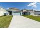 Modern home showcasing blue exterior, an attached garage, a well-manicured lawn, and a concrete driveway at 6230 Shavasana Rd, Clermont, FL 34714