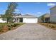 View of garage from brick paver driveway with green lawns on either side at 6383 Trailblaze Bnd, St Cloud, FL 34771