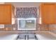 This cozy kitchen features tiled backsplash, wooden cabinetry, and a double sink with window views at 647 Holbrook Ave, Deltona, FL 32738