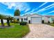 Well-maintained single-story home featuring a brick driveway, lush lawn, and tropical landscaping at 7978 Se 174Th Belhaven Loop, The Villages, FL 32162