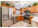 Efficient kitchen features stainless steel appliances, wood cabinets, and tiled backsplash at 7978 Se 174Th Belhaven Loop, The Villages, FL 32162