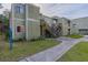 A weathered two-story exterior with a concrete walkway, lawn, and wood stairs that lead to the front door at 101 Scottsdale Sq # 101, Winter Park, FL 32792