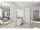 Well-lit bathroom featuring dual vanities, a glass-enclosed shower, and a soaking tub at 11866 Barletta Dr, Orlando, FL 32827