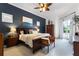 Cozy bedroom with a dark accent wall, wooden furniture, ceiling fan, and access to outdoor living area at 1613 Glenwick Dr, Windermere, FL 34786