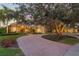 Beautiful estate home with lush landscaping, a circular driveway, and mature trees at sunset at 1613 Glenwick Dr, Windermere, FL 34786
