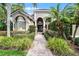 Beautiful home exterior with a landscaped walkway leading to the entrance, framed by lush greenery and palm trees at 1613 Glenwick Dr, Windermere, FL 34786