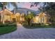 Stately home featuring a beautifully paved driveway, lush landscaping, and an inviting gated entrance at twilight at 1613 Glenwick Dr, Windermere, FL 34786