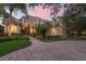 Elegant home with a well-manicured lawn, mature trees, and a brick driveway at 1613 Glenwick Dr, Windermere, FL 34786
