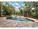 Sparkling screened-in pool with waterfall feature, lush tropical landscaping, and a brick paver patio at 1613 Glenwick Dr, Windermere, FL 34786