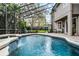 Outdoor pool and spa with a waterfall feature, screened enclosure, and lush landscaping at 1613 Glenwick Dr, Windermere, FL 34786