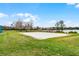 Sandy volleyball court with net surrounded by green grass and mature trees, providing a recreational amenity at 1613 Glenwick Dr, Windermere, FL 34786