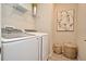 Efficient laundry room with modern washer and dryer, open shelving, decorative baskets, and an elegant art piece at 17667 Saw Palmetto, Clermont, FL 34714