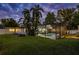 The backyard at dusk features a screened pool enclosure, landscaped greenery, and well-maintained lawn at 1832 Magnolia Ave, Winter Park, FL 32789