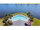 Aerial shot of the community pool, nestled by a serene lake and palm trees, creating a tranquil setting at 1862 Great Falls Way, Orlando, FL 32824