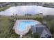 Aerial view of a community pool featuring plenty of lounge chairs, lush landscaping, and lake views at 2934 Wild Tamarind Blvd, Orlando, FL 32828