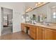 Bright bathroom with double sinks and a large mirror, featuring a view of the bedroom at 3603 Westover Cir, Leesburg, FL 34748