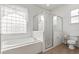 Bright bathroom featuring a glass-enclosed shower, tile floors, and a large soaking tub at 3603 Westover Cir, Leesburg, FL 34748