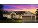 Inviting single-story home at sunset with a well-manicured lawn, complemented by a 3 car garage and neutral color palette at 3603 Westover Cir, Leesburg, FL 34748