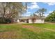 This home has a large backyard, a lawn, patio, mature trees, and partial fencing at 37 Spring Ln, Haines City, FL 33844