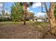 Spacious backyard with mature trees, grassy areas, and a view of the rear of the home at 37 Spring Ln, Haines City, FL 33844