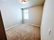 A carpeted bedroom with neutral walls features a window allowing natural light at 464 Patricia Alford Dr, Haines City, FL 33844