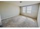 A carpeted bedroom featuring two windows with blinds and neutral colored walls at 464 Patricia Alford Dr, Haines City, FL 33844