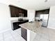 Kitchen showcasing an island with granite countertop, dark cabinets, and stainless steel appliances at 464 Patricia Alford Dr, Haines City, FL 33844