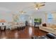 Bright living room with hardwood floors, ceiling fans, two sofas, and a large window providing natural light at 5347 Pecan Rd, Ocala, FL 34472