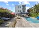 Backyard featuring a pool, lounge area, and tropical landscaping for outdoor relaxation and entertainment at 6480 S Atlantic Ave, New Smyrna Beach, FL 32169