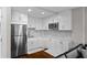 Modern kitchen featuring white cabinets, stainless steel appliances, marble countertops, and an attractive backsplash at 6480 S Atlantic Ave, New Smyrna Beach, FL 32169