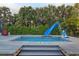 Backyard pool featuring a slide and a basketball hoop with wooden deck and surrounding greenery at 6480 S Atlantic Ave, New Smyrna Beach, FL 32169