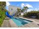 Modern home featuring a backyard pool with a slide and a basketball hoop with wooden deck at 6480 S Atlantic Ave, New Smyrna Beach, FL 32169