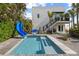 Modern home featuring a backyard pool with a slide and a basketball hoop with wooden deck at 6480 S Atlantic Ave, New Smyrna Beach, FL 32169