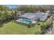An aerial view of a home's backyard with a screened-in pool, lush lawn, and mature landscaping at 6735 Edgeworth Dr, Orlando, FL 32819