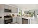 Open-concept kitchen with stainless steel appliances, gray cabinetry, and a view into the adjacent living area at 7359 Capstone Dr, Groveland, FL 34736