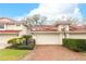 Charming townhome featuring a brick driveway, two-car garage, and a red tile roof at 7536 Fenwick Cove Ln, Orlando, FL 32819