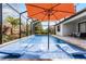 Refreshing screened-in pool with lounge chairs and a vibrant orange umbrella at 7916 Wandering Way, Orlando, FL 32836
