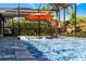 Stylish screened-in pool with lounge chairs, an umbrella, and lush greenery surrounding at 7916 Wandering Way, Orlando, FL 32836