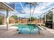 A view of the pool and surrounding brick perimeter, featuring a screened enclosure and tropical landscaping at 8661 Crestgate Cir, Orlando, FL 32819