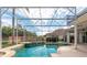 Outdoor view of a sparkling swimming pool and spa surrounded by lush landscaping and brick wall at 8661 Crestgate Cir, Orlando, FL 32819