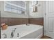 Bright bathroom featuring a soaking tub with tile surround and natural light at 9228 Cardinal Meadow Trl, Orlando, FL 32827