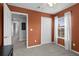 Bedroom featuring neutral carpet, an orange accent wall, and a closet with a view into the hallway at 9228 Cardinal Meadow Trl, Orlando, FL 32827