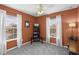 Bedroom with neutral carpet, orange walls, ceiling fan, and two windows dressed with white curtains at 9228 Cardinal Meadow Trl, Orlando, FL 32827