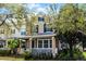 Charming tan two-story home with black shutters, welcoming front porch with white railings and mature tree and landscape features at 9228 Cardinal Meadow Trl, Orlando, FL 32827